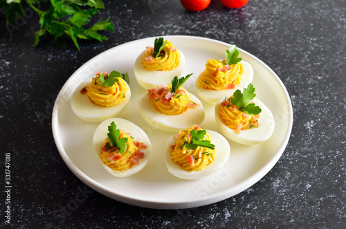 Stuffed eggs with egg yolk, bacon, mustard and parsley