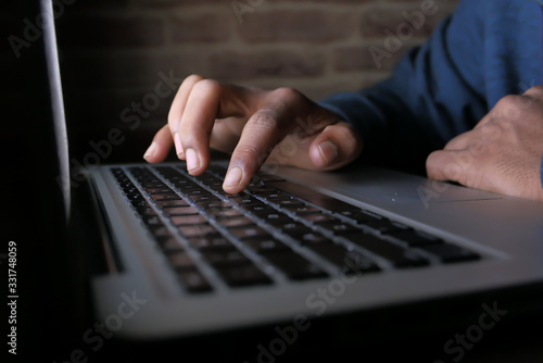 hooded hacker stealing data from laptop at night 