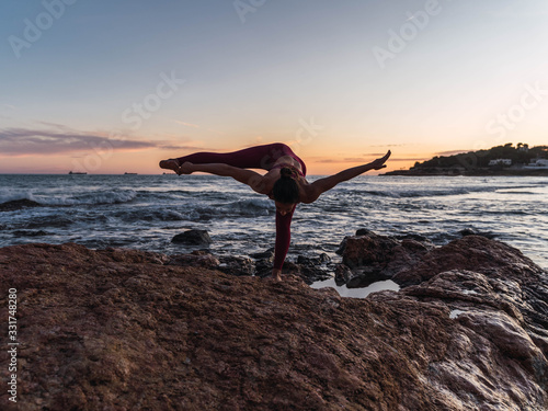 Young woman practicing the yoga pose Fire hydrant in front of the sea