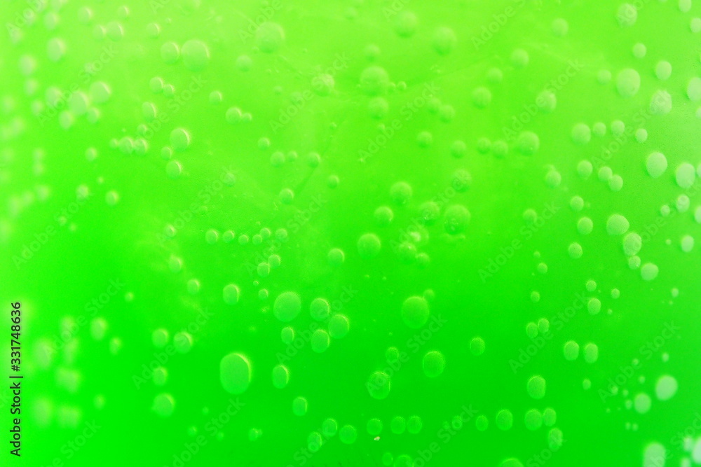 Closeup of beautiful bubbles in a clear glass with bright green juice inside for cold drink booster after work out or sun exposure outdoor. Food and drink preparing concept