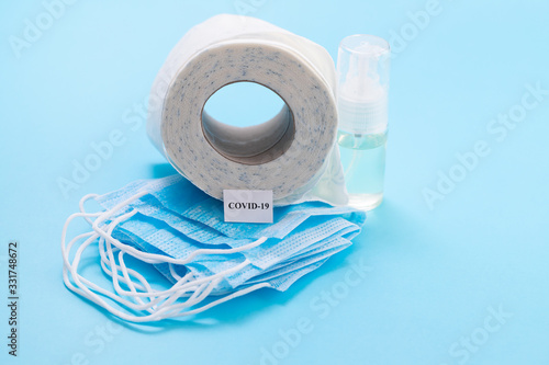 face mask, gloves, glass and toilet paper on blue background