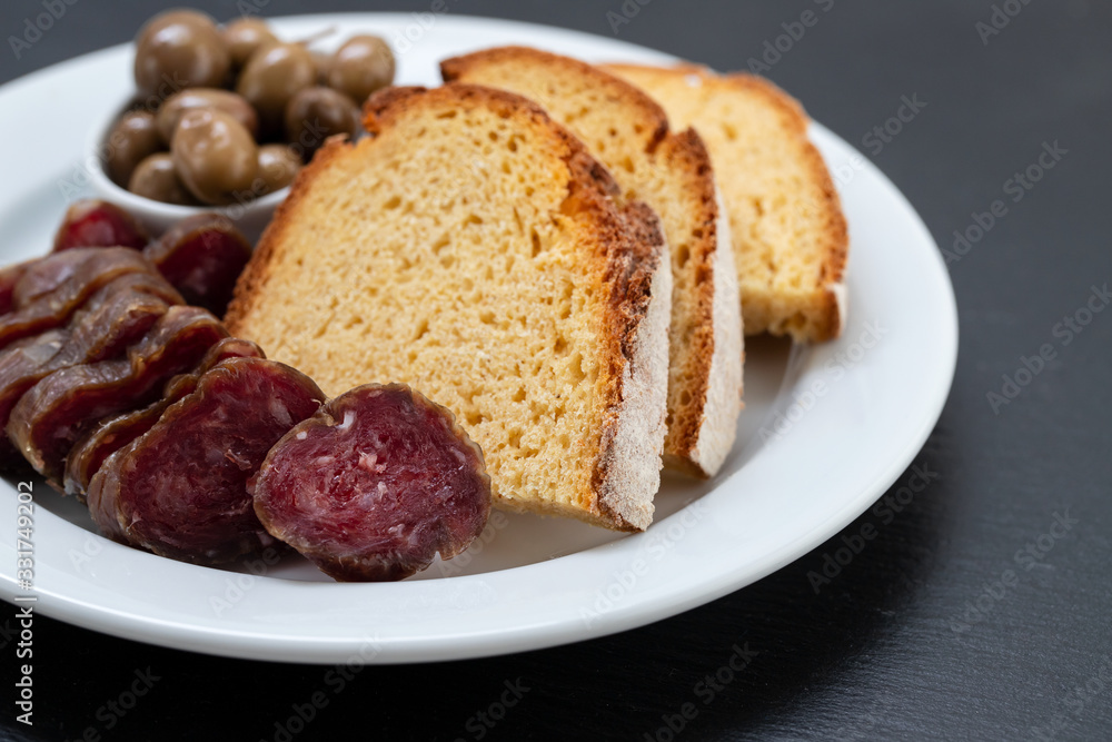 corn bread with smoked sausage and olives on white plate corn bread with smoked sausage and olives on white plate