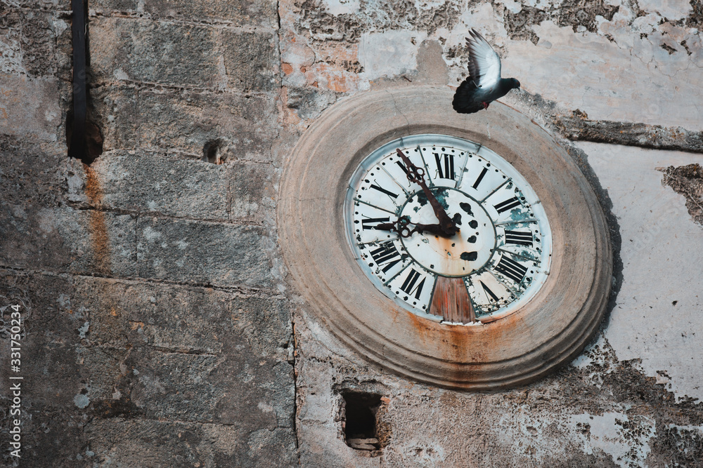 Time Flies: An Antique Circle Street Clock on an Old Wall with Pigeon on Vejer de la Frontera, Cadiz, Spain Time Flies: An Antique Circle Street Clock on an Old Wall with Pigeon on Vejer de la Frontera, Cadiz, Spain