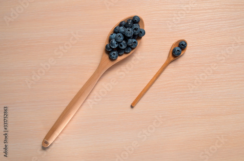 Fresh blueberries lie in a wooden spoon on a natural wooden background. Eco products for human health. Healthy eating concept flat lay. Copy spase