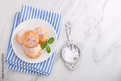 Profiteroles with custard decorated with mint on a marble background
