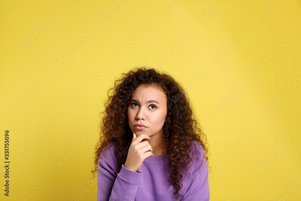 Pensive African-American woman on yellow background. Thinking about difficult question Pensive African-American woman on yellow background. Thinking about difficult question