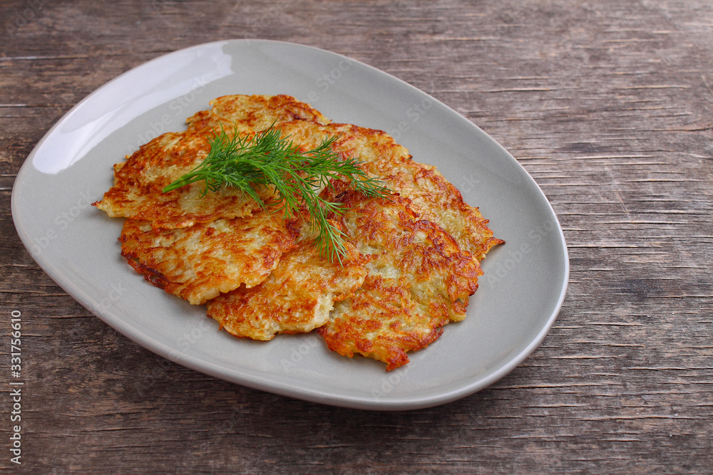 Potato pancakes in a plate decorated with dill on a rustic background Potato pancakes in a plate decorated with dill on a rustic background