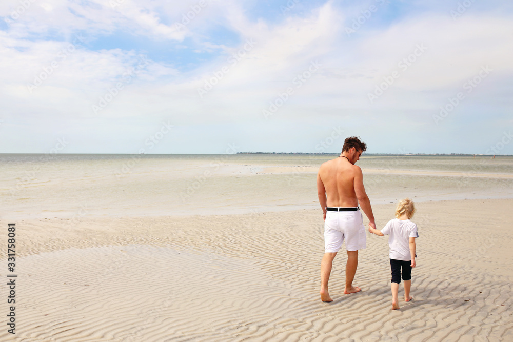 Father and His Young Child Walking on A White Sand Sandbar in the Ocean at a Public Beach
