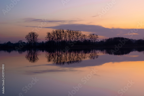 Purple-pink sky and cloud over the lake  trees on the horizon  view after sunset