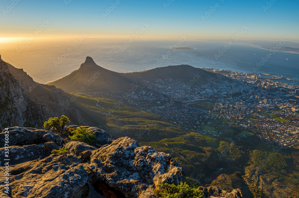Cityscape of Cape Town city and Lions head mountain peak at sunset with the Indian Ocean in the background as seen from the Table Mountain National Park, Western Cape Province, South Africa.