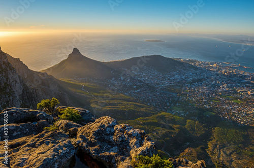 Cityscape of Cape Town city and Lions head mountain peak at sunset with the Indian Ocean in the background as seen from the Table Mountain National Park, Western Cape Province, South Africa.