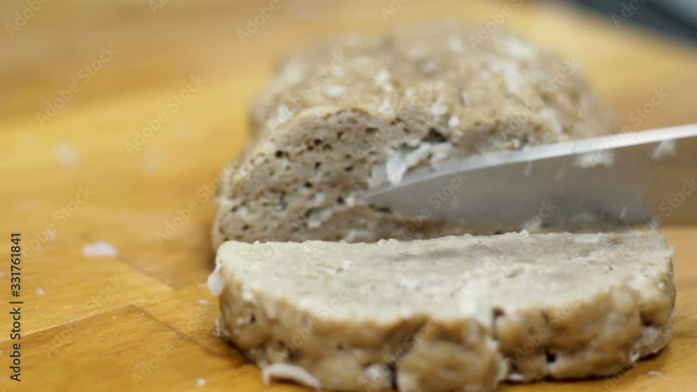 Woman hand cutting slices of homemade seitan. Selective focus Woman hand cutting slices of homemade seitan. Selective focus