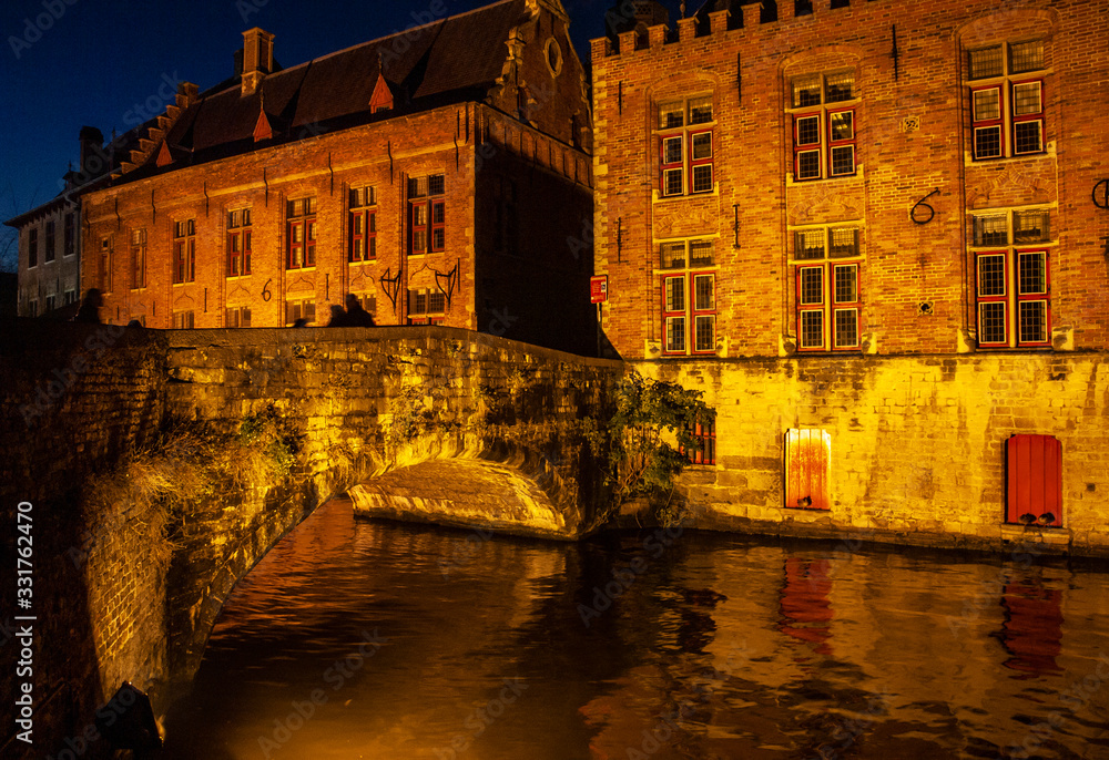 Vista nocturna de un puente de piedra sobre un canal de Brujas