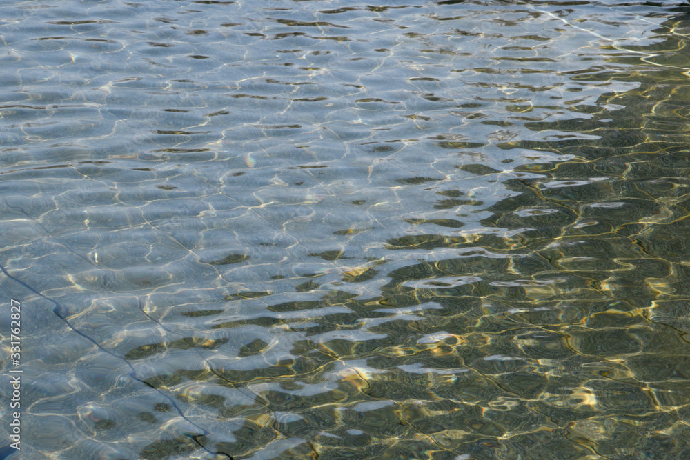The calm surface of the water, rays of light are reflected on it, finely and beautifully. Water surface of transparent water in a reservoir. The calm surface of the water, rays of light are reflected on it, finely and beautifully. Water surface of transparent water in a reservoir.