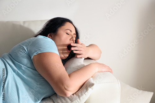 Bild auf Leinwand Lazy overweight woman resting on sofa at home
