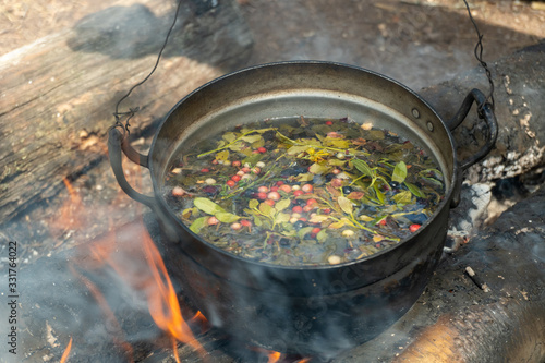 A pot with a herbal tea on campfire