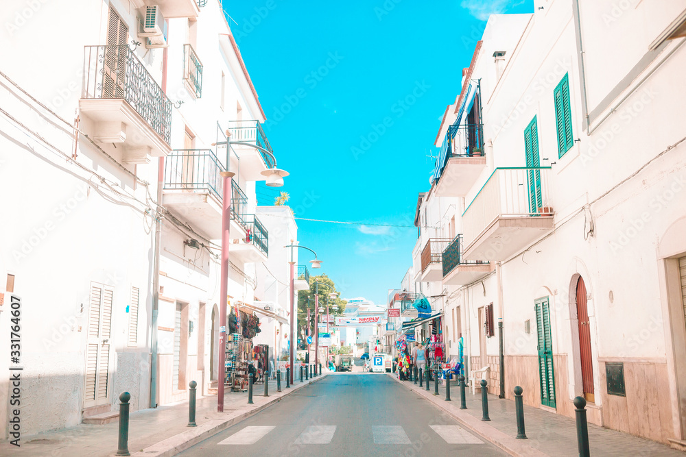 Obraz premium The narrow streets of the island with blue balconies, stairs and flowers.