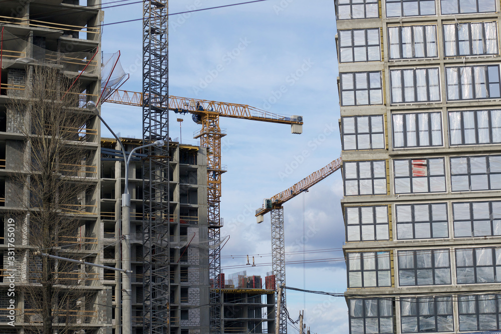 High-rise building under construction. Reinforced concrete frame. Start of installation of double-glazed windows. Visible construction cranes. High-rise building under construction. Reinforced concrete frame. Start of installation of double-glazed windows. Visible construction cranes.