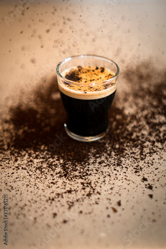 Photos taza de café recién hecha, espolvoreada con su propio café y una luz cálida de arriba para darle contraste y que se aprecien bien sus matices