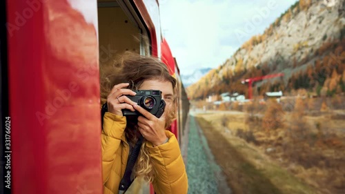 Wallpaper Mural Excited happy woman, smiling and laughing leans out of train carriage window. Traveling young woman with photocamera during amazing trip on bernina express train Torontodigital.ca