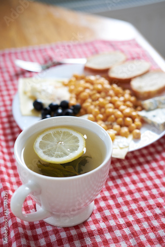 green tea with lemon with breakfast set of fried egss with lentils  olives  blue cheese on a background