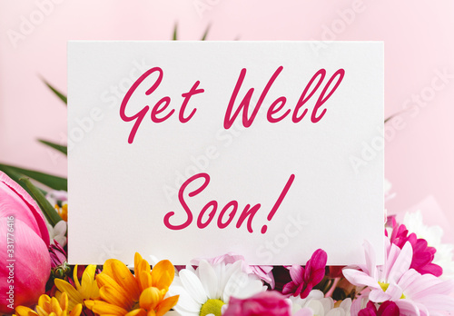 Get Well Soon card in flower bouquet on pink background. Stock photo mock up for text. photo