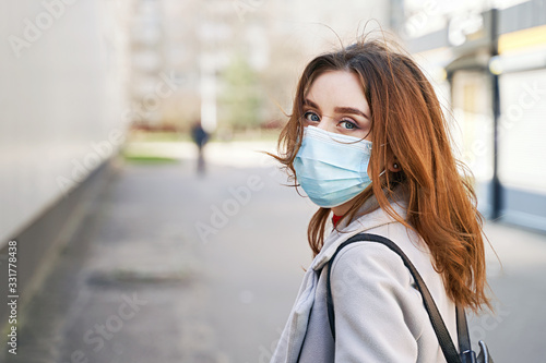 Obraz na płótnie Young woman with beautiful blue eyes and disheveled hair wearing protection face mask against coronavirus MERS-Cov, Novel coronavirus 2019-nCoV. Concept of coronavirus quarantine and pandemic. w salonie