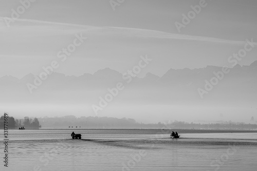 fisherboat in the morning with alps panorama in background monochron and quiet sunrise scenery photo