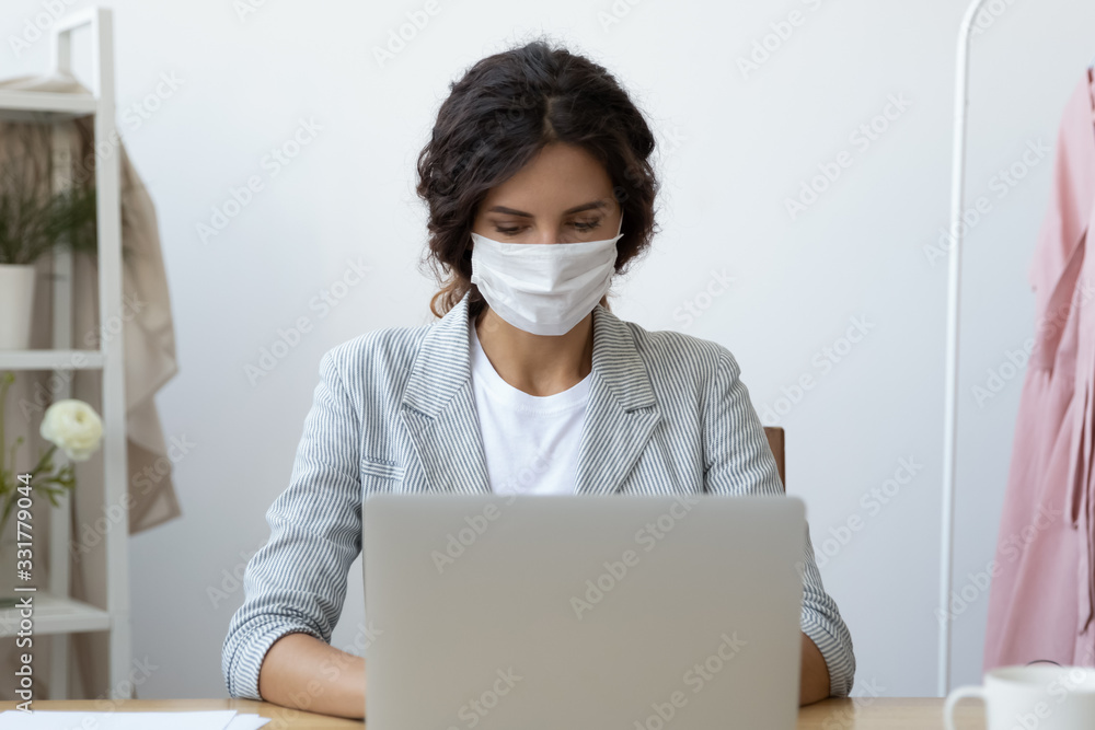 Young business woman wearing face mask working on computer seated at workplace desk in office room protecting herself from getting grippe vs COVID-19 corona virus pandemic infectious disease concept - obrazy, fototapety, plakaty 