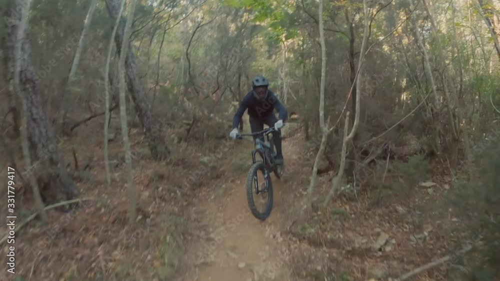 Mountain biker rushes along the steep trail in forest on a sunny day. Extreme sport, healthy lifestyle. View from first person perspective POV. Mountain biker rushes along the steep trail in forest on a sunny day. Extreme sport, healthy lifestyle. View from first person perspective POV.