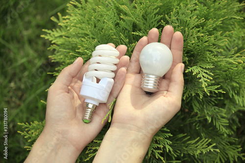 hands are holding a light bulb and energy-efficient analog