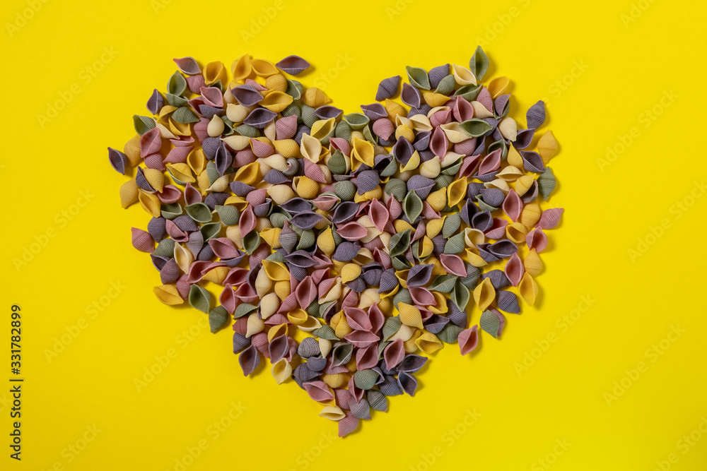 Heart of Pasta Conchiglie Rigate, mix of colorful uncooked shells with spinach and tomatoes. Textured Italian food background concept. Top view flat lay close up copy space Heart of Pasta Conchiglie Rigate, mix of colorful uncooked shells with spinach and tomatoes. Textured Italian food background concept. Top view flat lay close up copy space