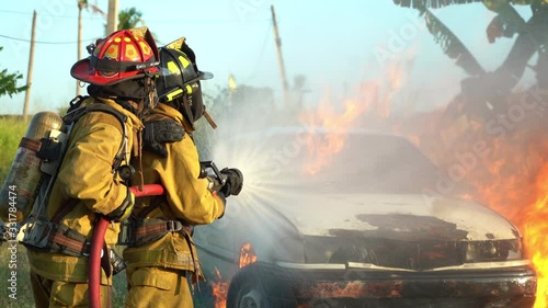 firefighter using spraying water to the fire buring in car accident
