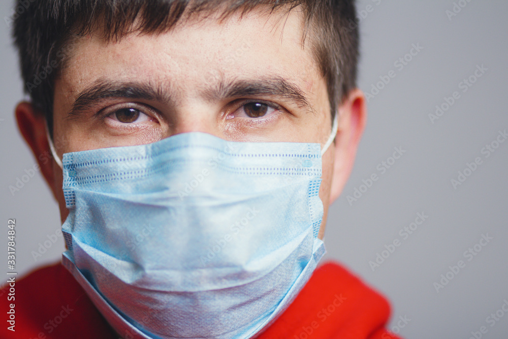 portrait of serious young man face in a protective medical mask on a gray studio background, concept of health and quarantine measures portrait of serious young man face in a protective medical mask on a gray studio background, concept of health and quarantine measures