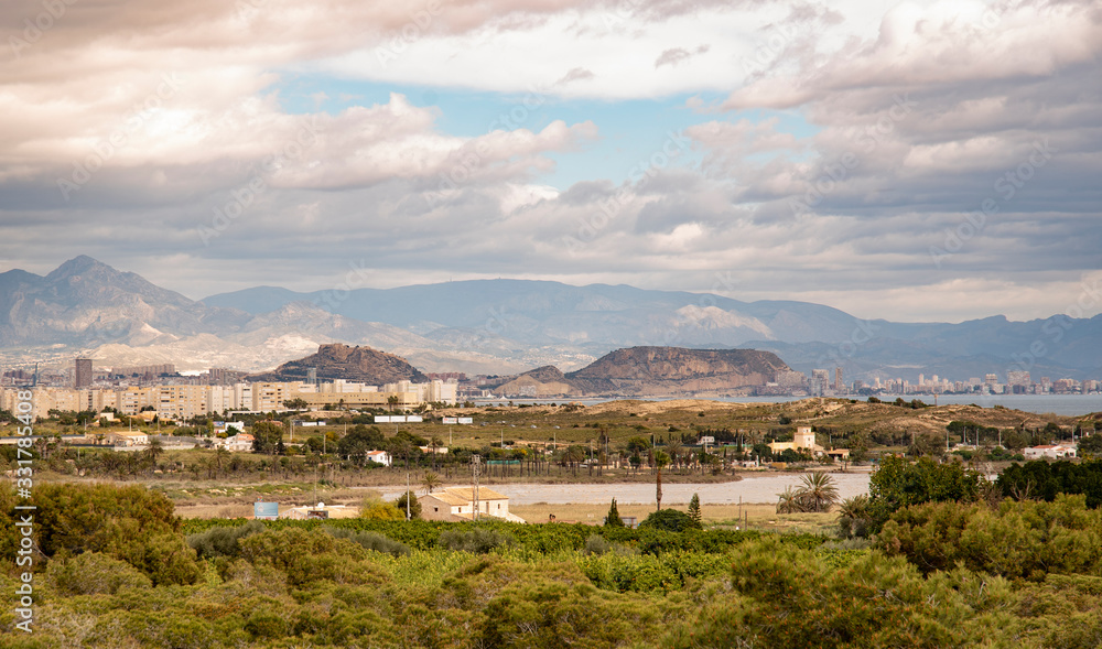 Obraz premium Panoramic view of Alicante, Valencian Community, Spain. Its skyline can be seen perfectly through the dunes and the Mediterranean landscape with the mountains in the background