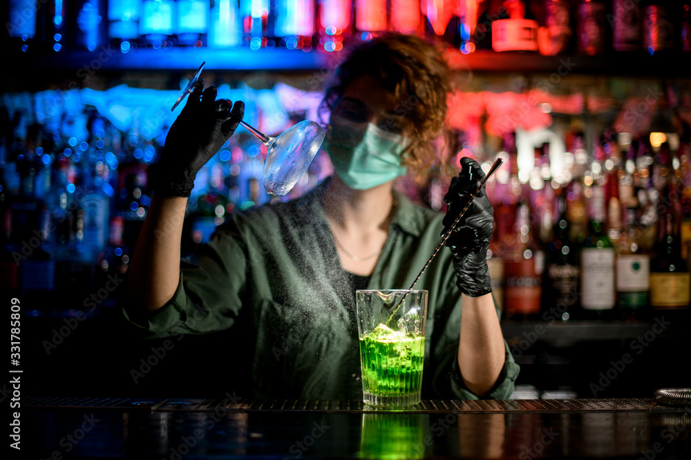 young girl at bar counter in medical mask and black gloves accurate holds glass and spray to it. - obrazy, fototapety, plakaty 