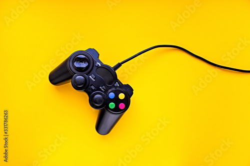 Black game controller for a console video game on a yellow background
