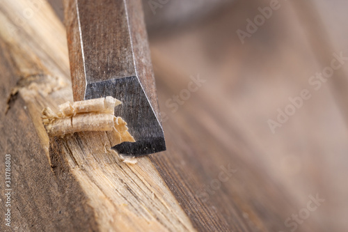 Chisel work in wood and raw wood shavings. Tools and accessories in a carpentry shop.