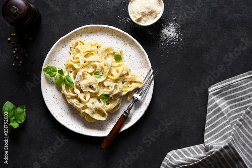 Tagliatelle pasta with cheese sauce and basil in a plate on the kitchen table. photo