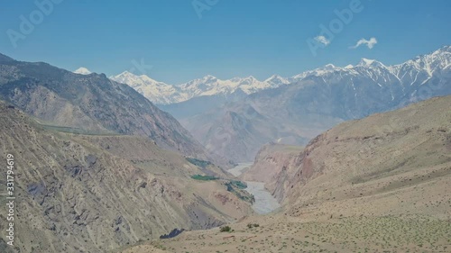 Birds eye panorama of wide deep river gorge with snowy mountains in blue mist