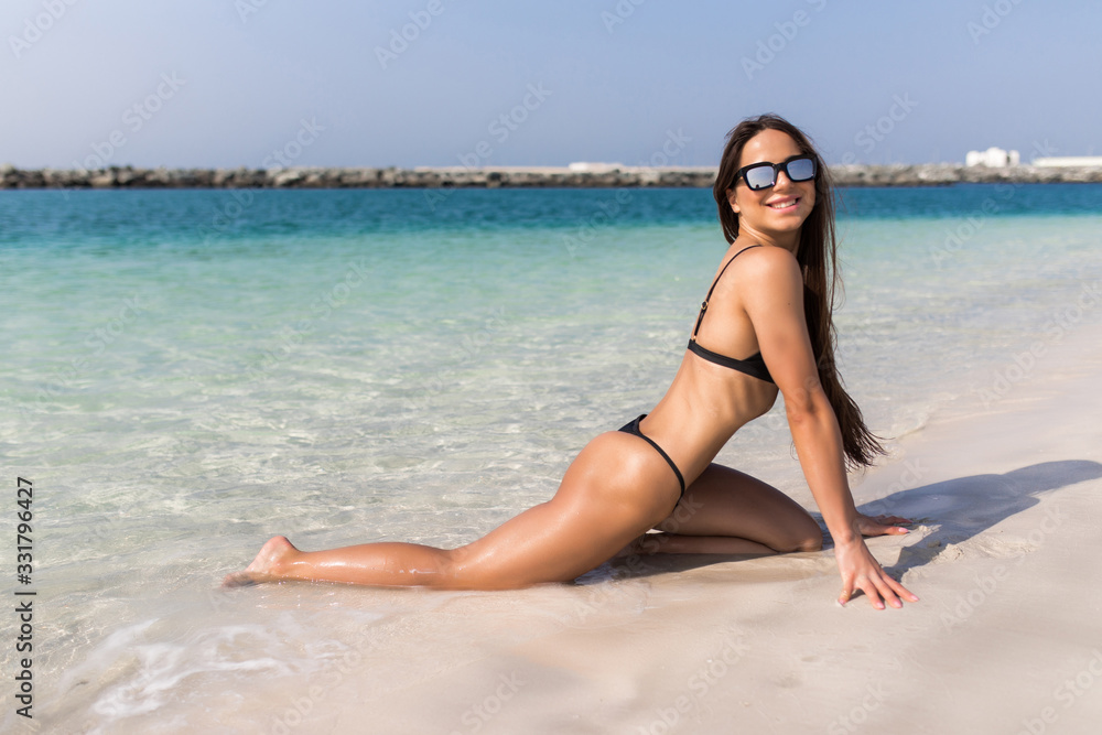 Portrait of pretty young suntanned woman lying on the beach of the tropical island.