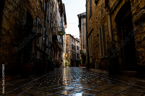 Fototapeta Naklejka Na Ścianę i Meble -  A narrow small street in the old medieval center of a French town in the morning after rain (Vence, France)