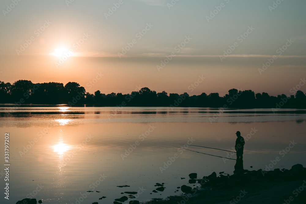 Fisherman at dawn fishing on a fishing rod Fisherman at dawn fishing on a fishing rod