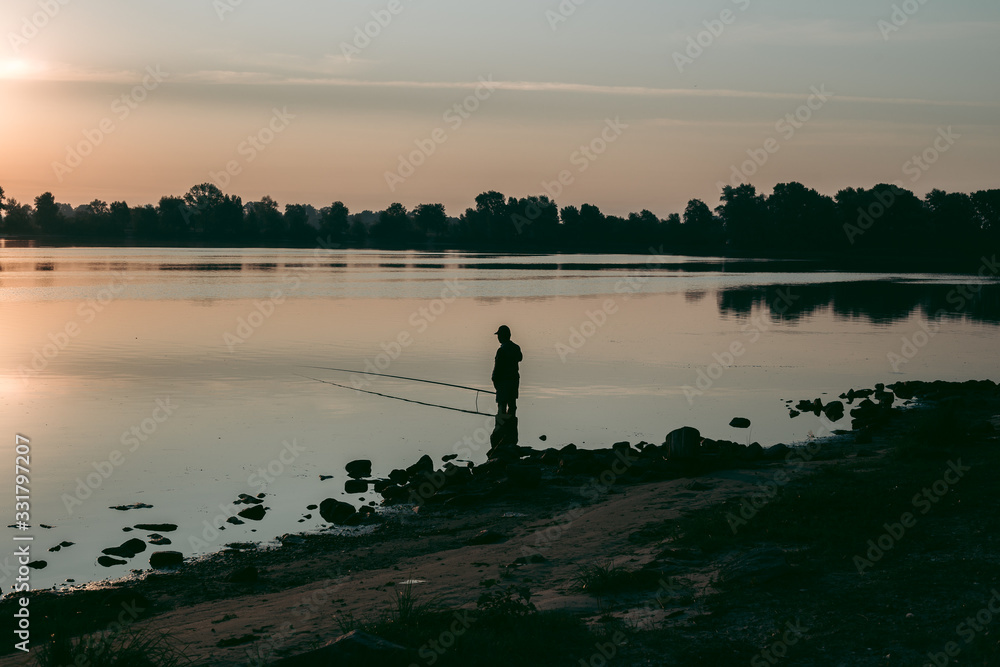 Obraz premium Fisherman at dawn fishing on a fishing rod