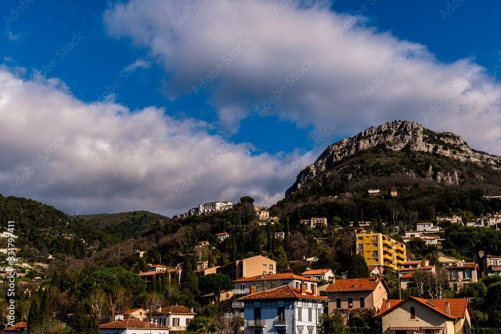 The panoramic view of Vence apartment buildings in the low Alps below an alpine cliff under the clear bright blue sky on a sunny day