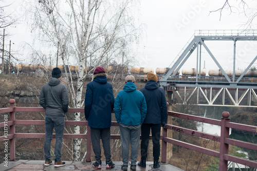 Four guys stand on the bridge near the river © Hennadii