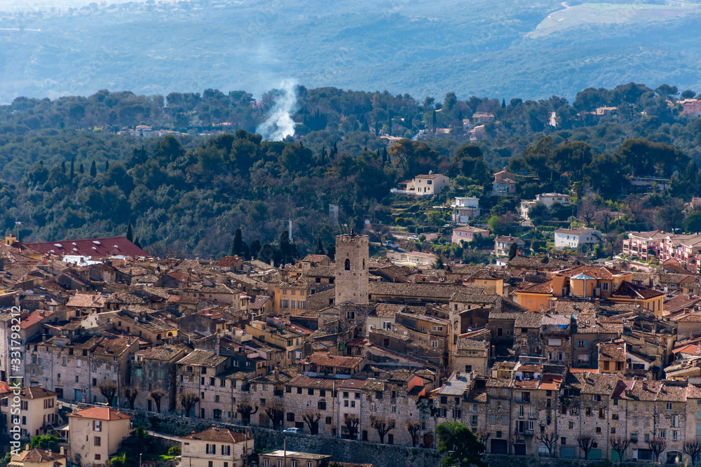 A close-up panoramic view of the old French town Vence and its medieval architecture and buildings with the low Alps mountains hills and forests in the background (Provence / Riviera / Côte d'Azur)