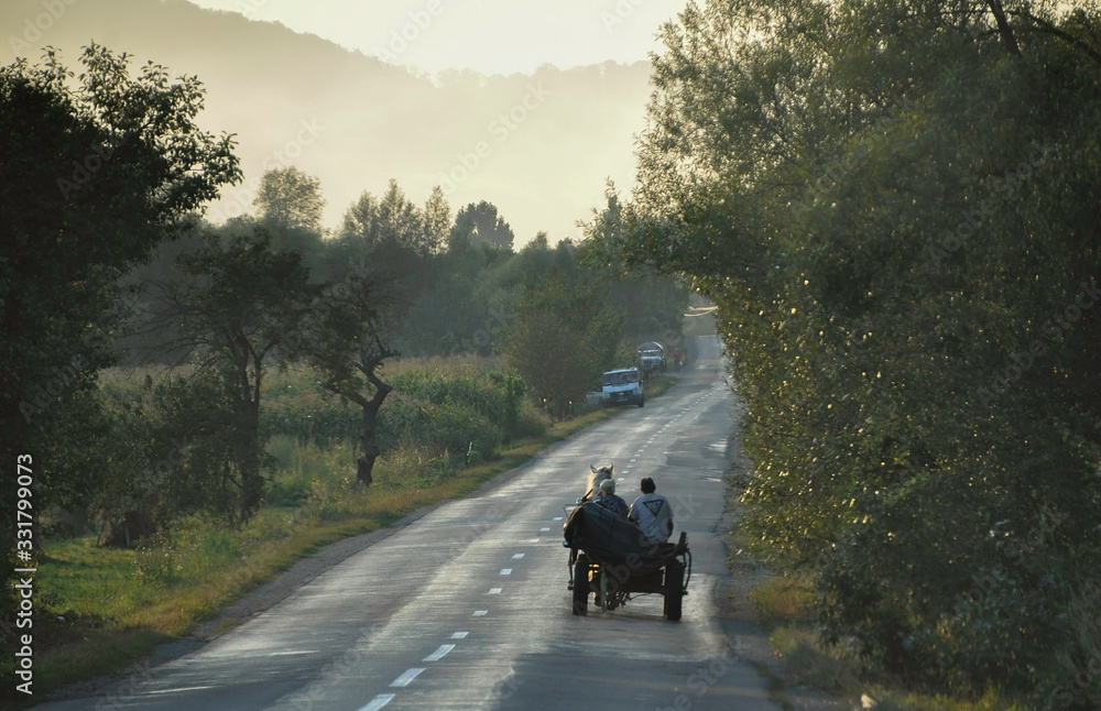 Maramures, Romania, Europe. August 2018. A couple of strangers in a horse carriage on the road head home after working all day on the land.