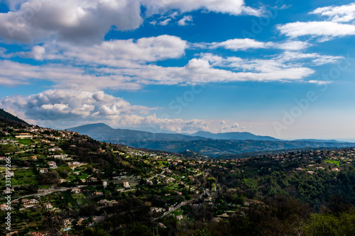 A wide   high angle panoramic view of Saint-Jeannet buildings and other towns covering the low Alps mountains hills with the mountain ranges in the haze  French C  te d Azur  Provence  Riviera 