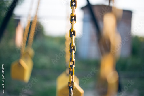 Yellow rubber swing on chains in the backyard